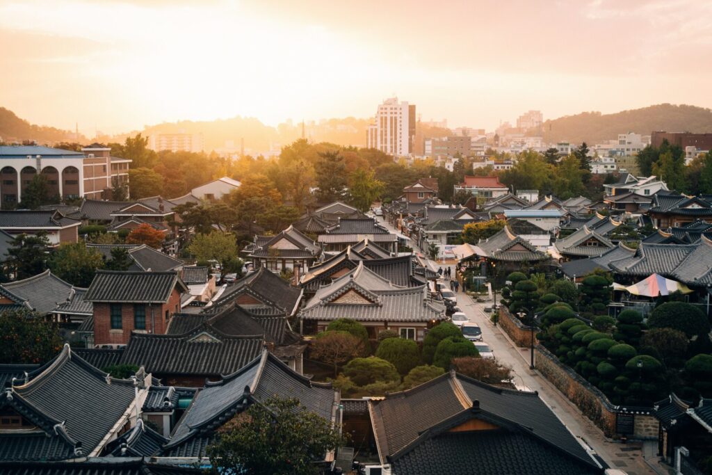 전주 이름 유래를 소개하는 전주한옥마을 전경, 기와지붕과 현대 도심이 함께 보이는 풍경