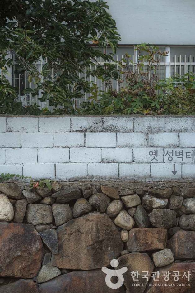 강릉 명주동 거리의 옛 성벽과 흰색 벽돌 담장이 함께 하는 모습. 강릉 이름 유래의 과거와 현재가 함께 하는 공간
