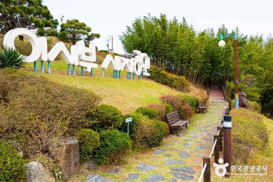 강원특별자치도 삼척시 이사부사자공원의 입구. 언덕에 설치된 이사부사자공원 조형물과 산책로, 나무와 대나무숲이 보이는 풍경.